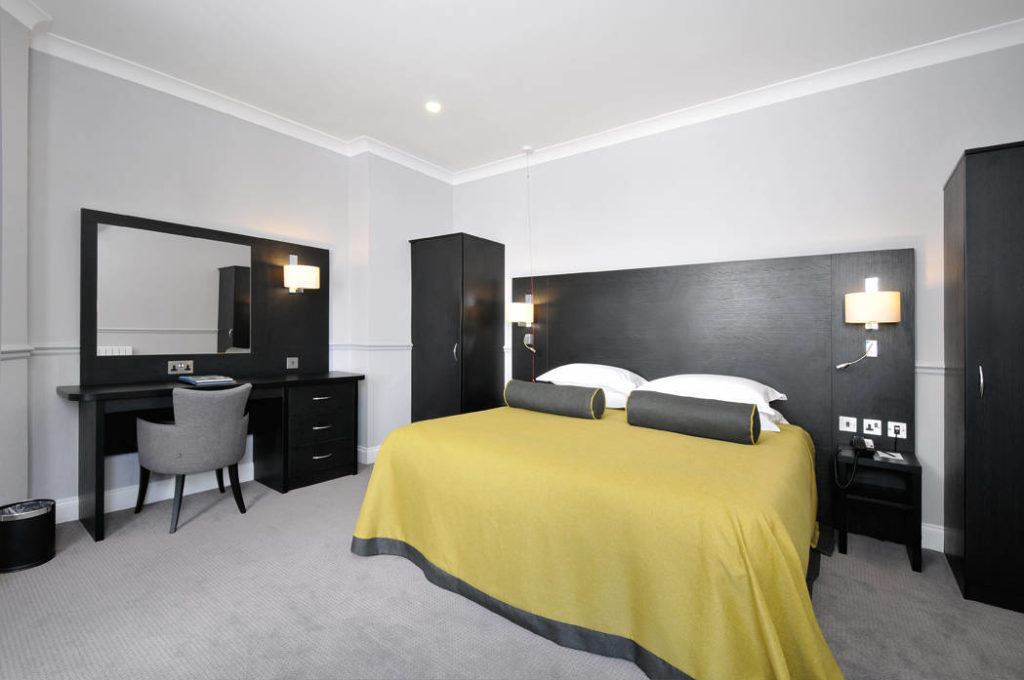 Bromley Court Hotel - A black and yellow bedroom with a bed and desk in Bromley.