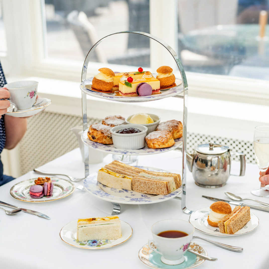 Bromley Court Hotel - Afternoon tea service with an assortment of sandwiches, scones, and pastries on a three-tiered stand, accompanied by tea and champagne.